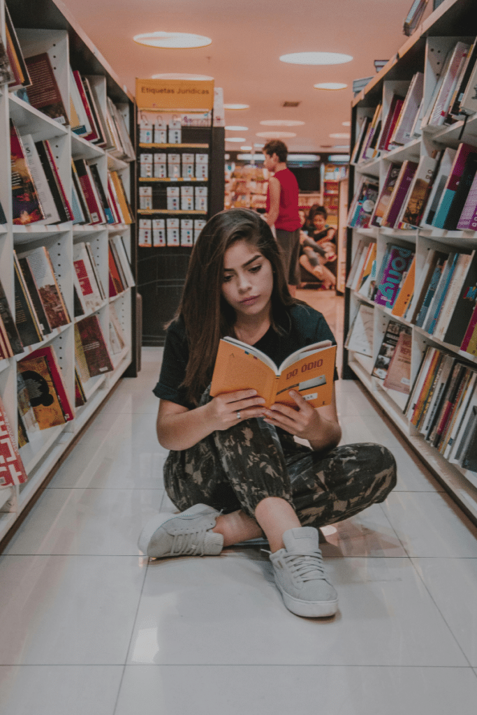 Dyslexic student reading cross-legged in the library.