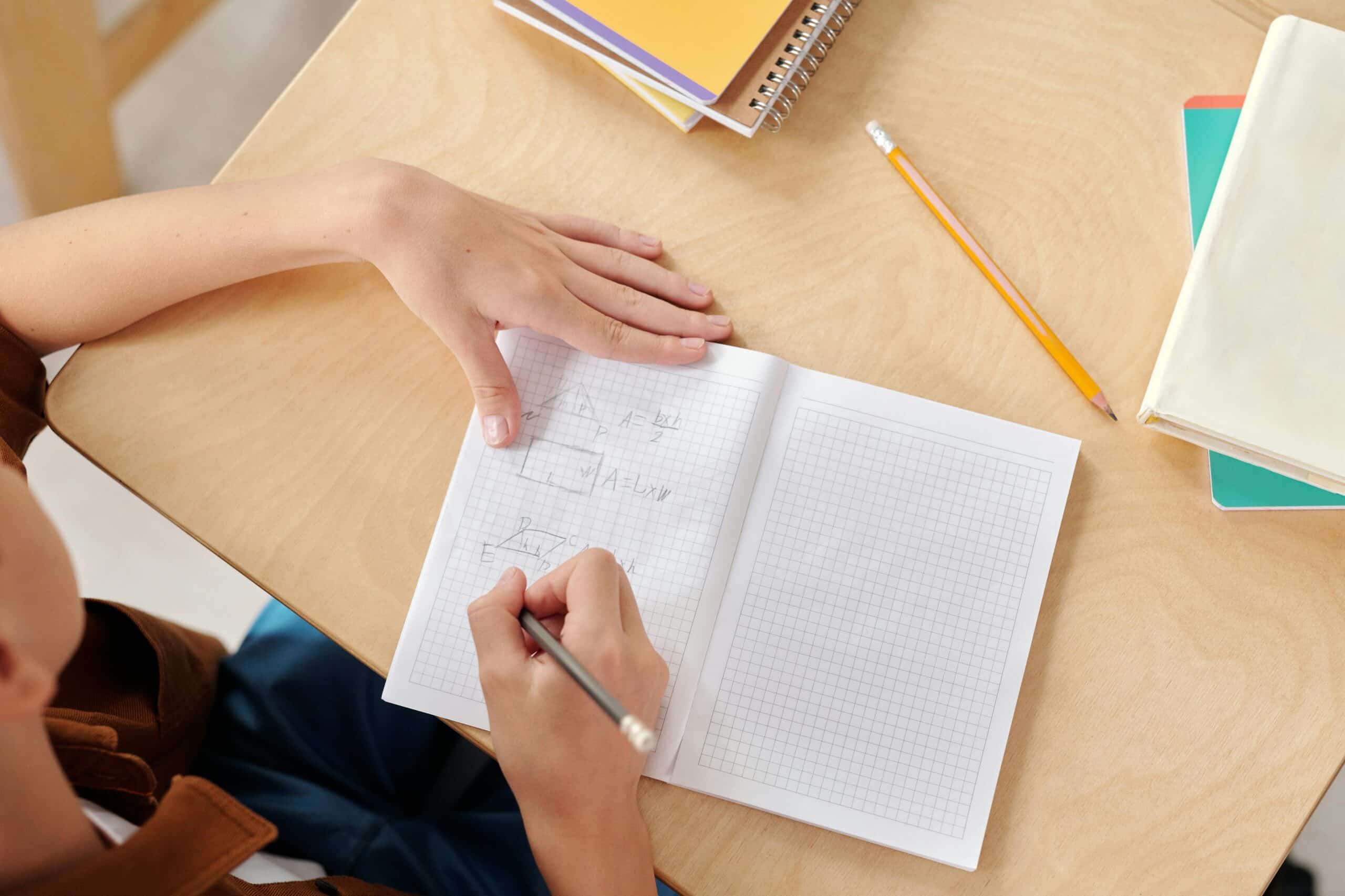 GCSE student with ADHD writing revision notes at a desk.